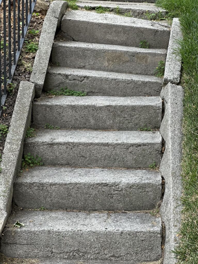 Cracked and deteriorated concrete front steps showing structural damage before replacement.