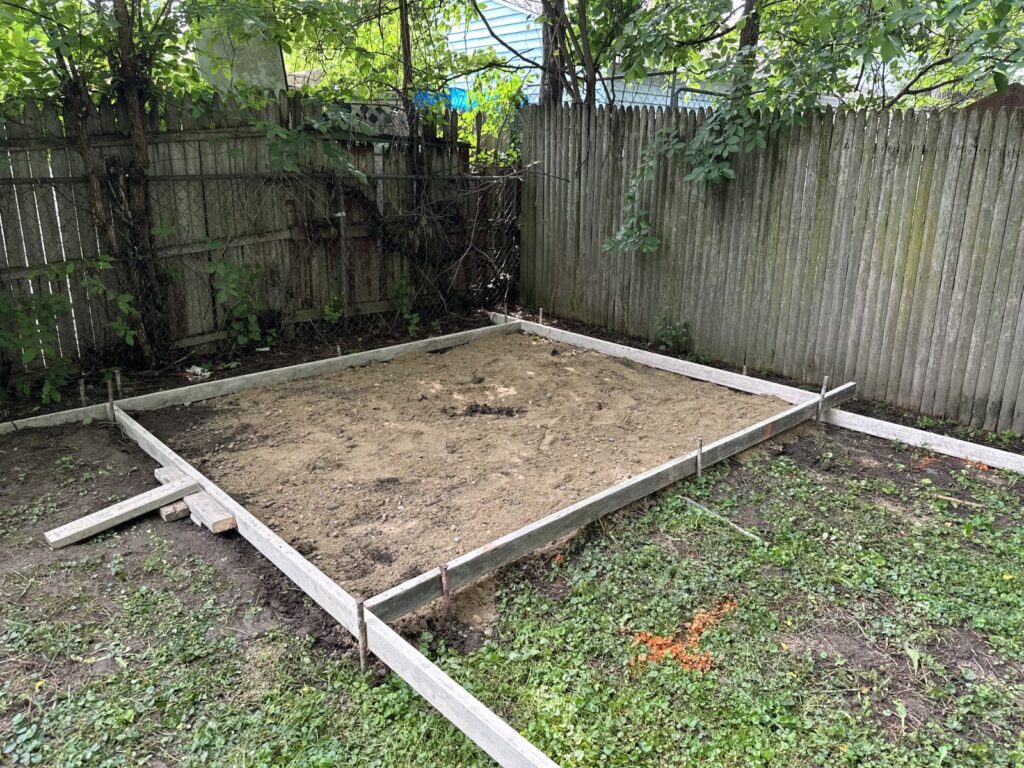 Backyard patio area graded and framed with wooden forms before concrete placement.